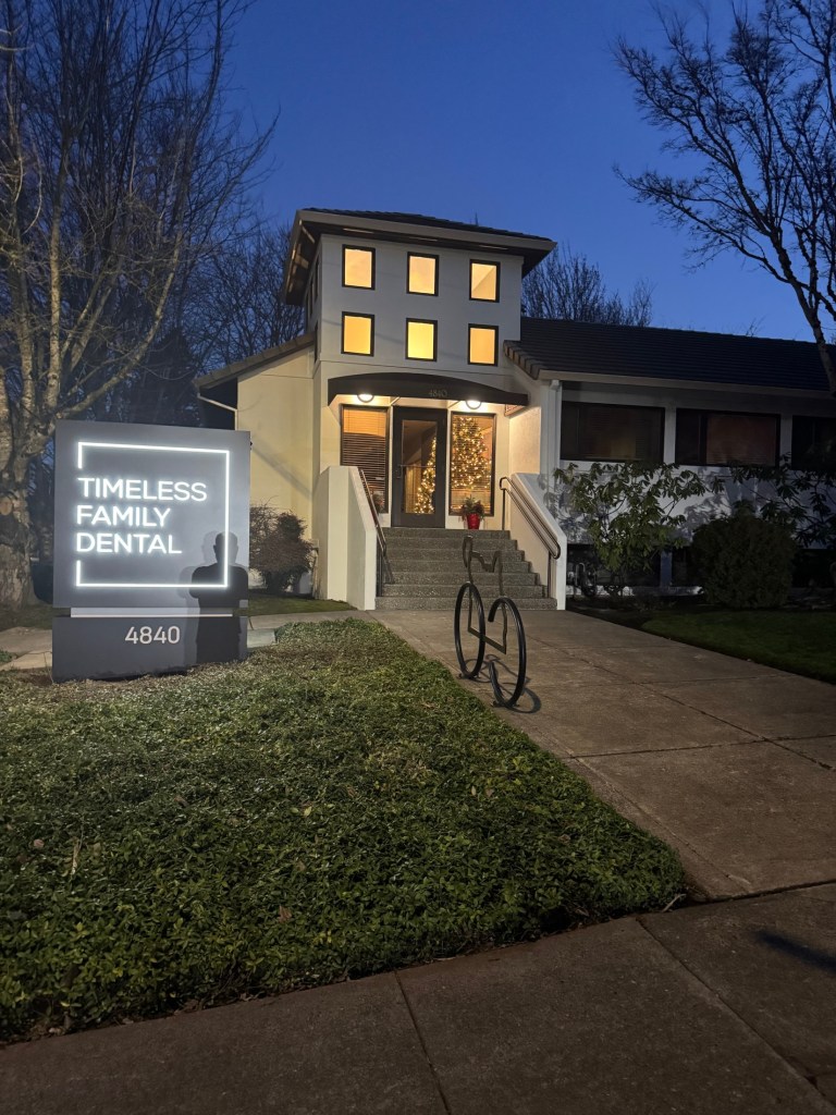 Timeless Family Dental exterior at dusk, lit sign and entrance.